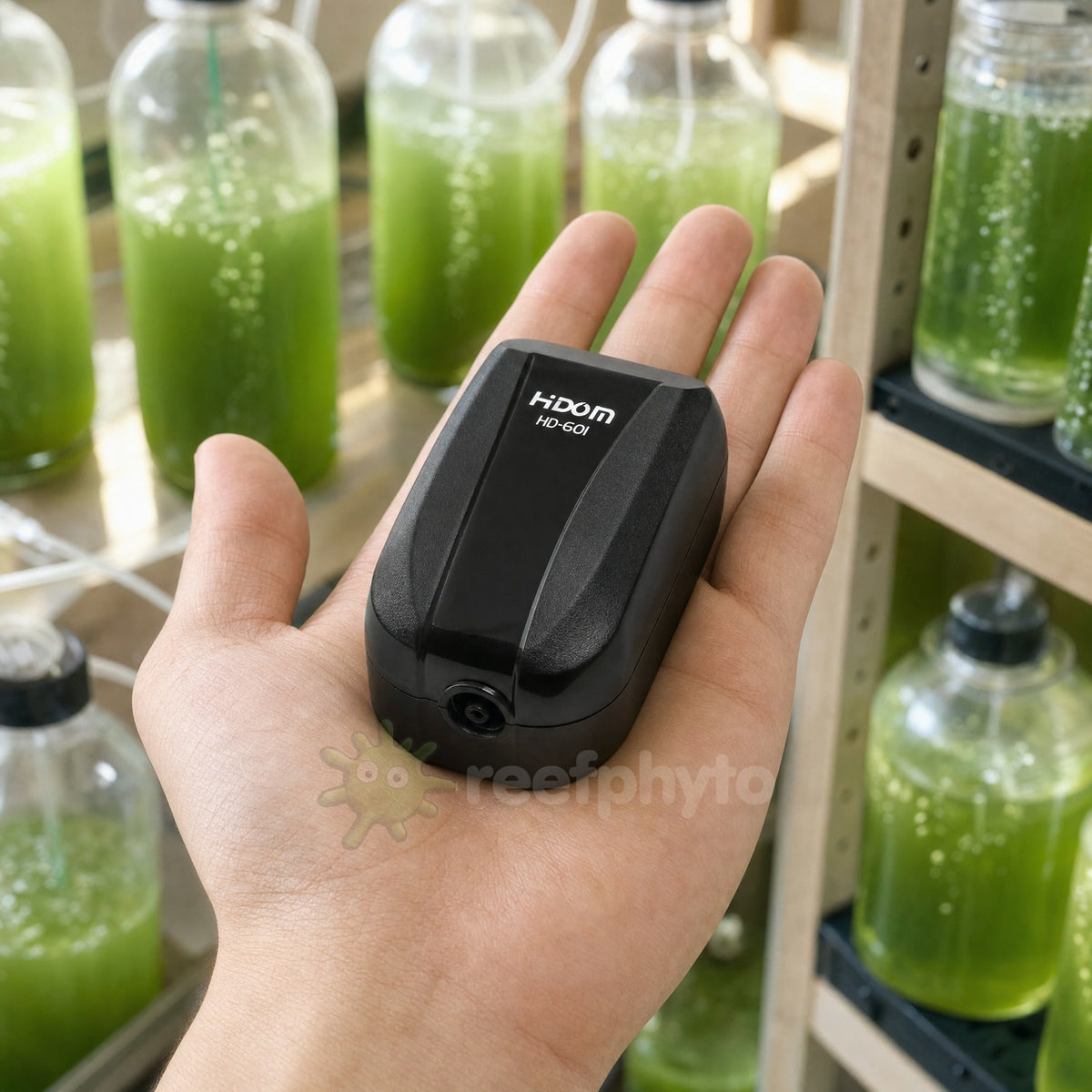 Hidom HD-601 air pump held in the palm of a hand to show its compact size