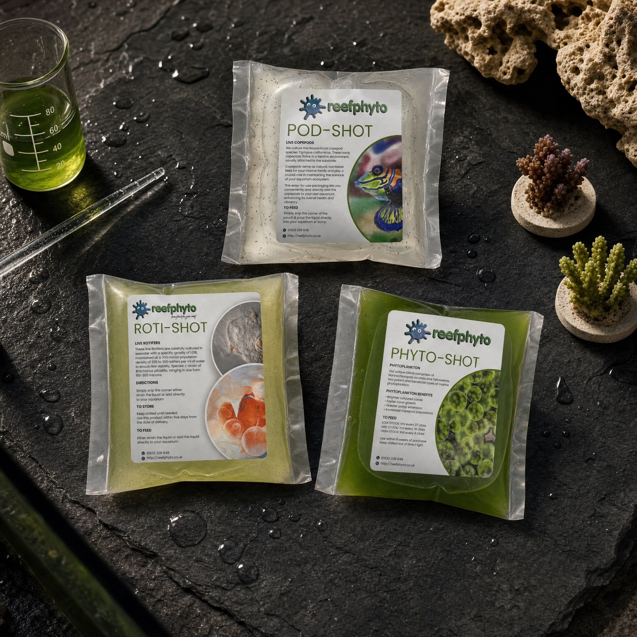 Reefphyto Reef Shot range flat-lay - Pod-Shot live copepods, Roti-Shot live rotifers and Phyto-Shot phytoplankton pouches on dark slate with reef aquarium equipment