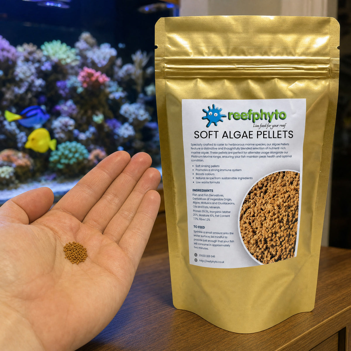 A pinch of Reefphyto Soft Algae Pellets in the palm of a hand beside the gold pouch
